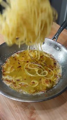 someone is tossing noodles into a frying pan