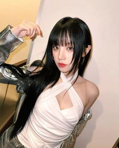 a woman with long black hair and white top posing in front of a mirror wearing silver gloves