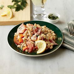 a green plate topped with lots of food next to a glass of wine and silverware