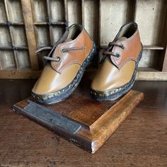 "Mounted miniature leather clogs, Lancashire Weavers. Beautifully made tan leather model shoes with chunky black 'clog' soles. One shoe has it's original leather lace, the other shoe has a brown cord replacement.  The shoes are mounted on a wooden base with a well-worn label that (would have) read 'Lancashire Weavers Clogs'.  In good vintage condition. Minor signs of wear but no visible damage.  Dimensions: Width/depth: 145mm (5 3/4\") Height: 120mm (4 3/4\") Weight: 515g Shoe length: 135mm (5 1/4\") Shoe width: 60mm (2 3/8\") Shoe height: 65mm (2 1/2\")" Black Clogs, Model Shoes, Leather Clogs, Wooden Base, Leather Lace, Womens Oxfords, Leather And Lace, Collectible Dolls, Tan Leather