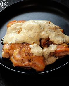 a black plate topped with meat covered in gravy