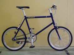 a blue bicycle parked against a yellow wall