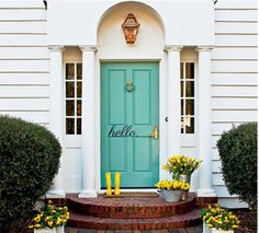 a blue door with yellow flowers on the steps and potted planters in front