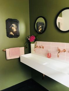 a bathroom with two sinks, mirrors and pink towels hanging on the wall above them