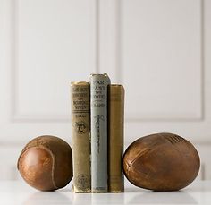 three books and two leather balls on a table