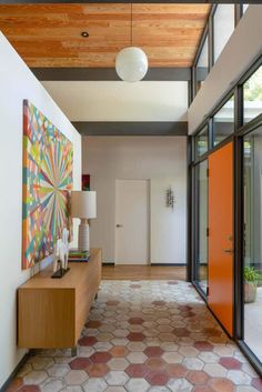 an image of a hallway with glass doors and artwork on the wall in front of it