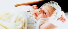 a baby is wearing a bonnet and looking up at the camera while laying on its back