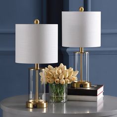 two lamps sitting on top of a table next to a vase with flowers in it