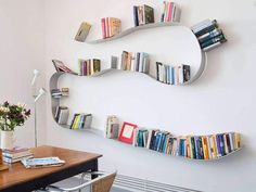 a room with a table, chairs and bookshelves on the wall in front of it