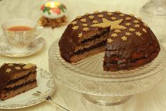 a cake on a plate with a slice cut out and two tea cups in the background