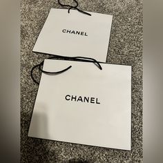 two chanel shopping bags sitting on the floor next to each other with black string