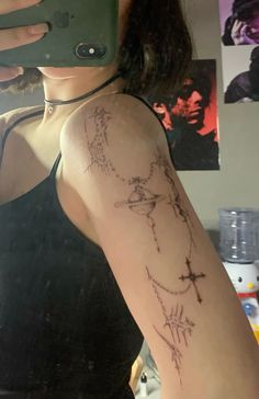 a woman is taking a selfie with her cell phone and wearing a cross tattoo on her arm