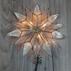 a lighted star decoration on a wooden surface with lights in the center and two wire wrapped around it