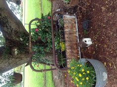 an old metal bench with flowers in it and some plants growing out of the back