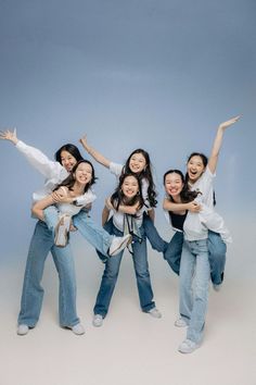 four young women are posing for a photo with their arms in the air and smiling