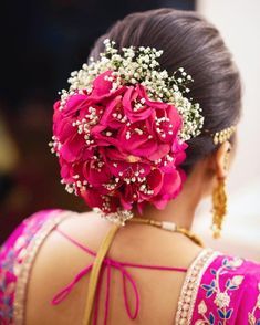 the back of a woman's head with flowers in her hair and jewelry on it