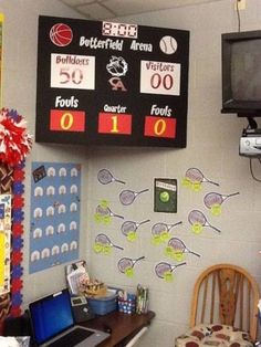 a desk with a laptop computer sitting on top of it in front of a scoreboard