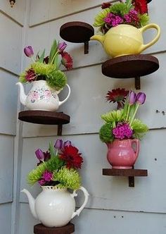 a number of vases with flowers in them hanging on the side of a building