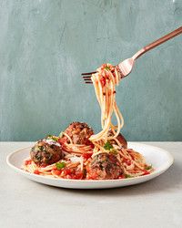 a plate of spaghetti with meatballs and tomato sauce being lifted from a fork over it