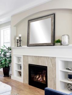 a living room with a fire place and mirror on the fireplace mantel above it