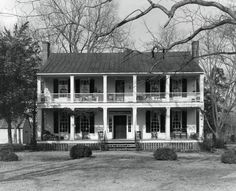 an old black and white photo of a two story house with porches on the second floor