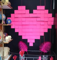 some pink sticky notes hanging from a string on a black wall with other items in the background