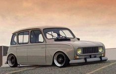 an old grey station wagon parked in a parking lot next to a wall and fence