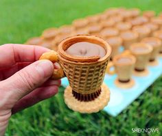 a person is holding up a cookie in front of some cups