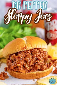 a close up of a sloppy joe sandwich on a table with chips and ketchup