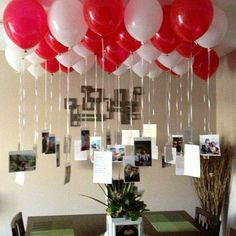 red and white balloons hang from the ceiling above a dining room table with pictures on it