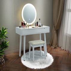 a white vanity table with a stool and lighted mirror on it in front of a window