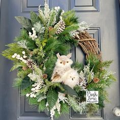 a wreath with an owl and pine cones on the front door is adorned with greenery