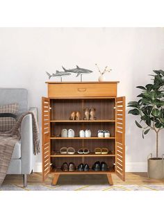 a wooden shoe rack with shoes on it in front of a couch and potted plant