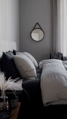 a bed with black and white striped sheets in a bedroom next to a mirror on the wall