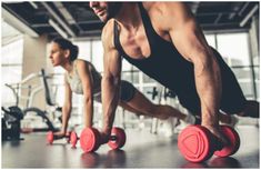 two men are doing push ups with red dumbbells in the gym while another man watches