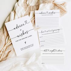 two wedding advice cards with calligraphy on them next to some feathery material,