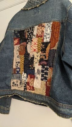 an old patchwork jean jacket is hanging on the wall, and it has been stitched together