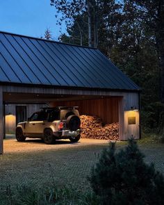 a truck parked in front of a garage with logs stacked on the ground underneath it