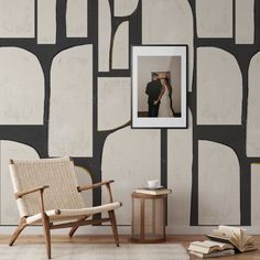 a couple kissing in front of a wall with geometric shapes on it and an open book next to the chair