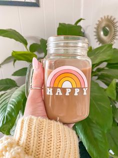 a person holding up a jar with a happy sticker on it and a potted plant in the background