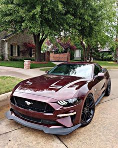 a maroon sports car parked in front of a house