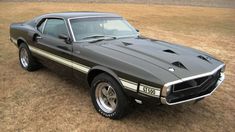 an old muscle car parked in a field