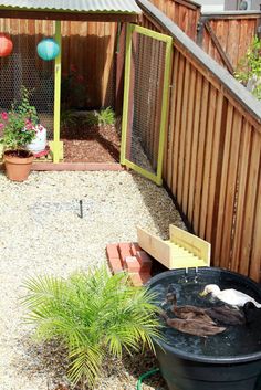 a backyard area with a fence, potted plants and a trash can in it