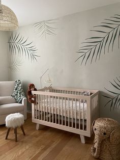 a baby's room with palm leaves painted on the wall