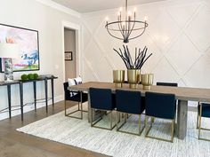 a dining room table with blue chairs and a chandelier