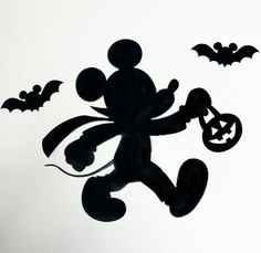 a mickey mouse silhouette with bats and pumpkins on it's side, in front of a white background