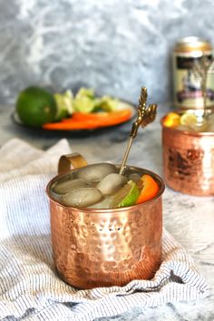 two copper mugs filled with drinks on top of a table