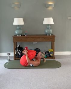 a woman is doing yoga on the floor in front of a table with shoes and lamps