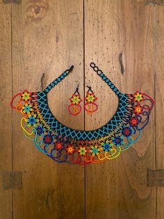 a multicolored necklace and earring set on a wooden floor with wood planks