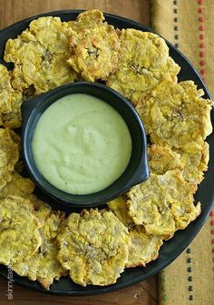 a black plate topped with fried food next to a green dip